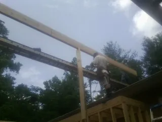 Carpenter setting a ridge beam over a new addition frame — Ice Dam Removal by Roofing Brothers in Prague