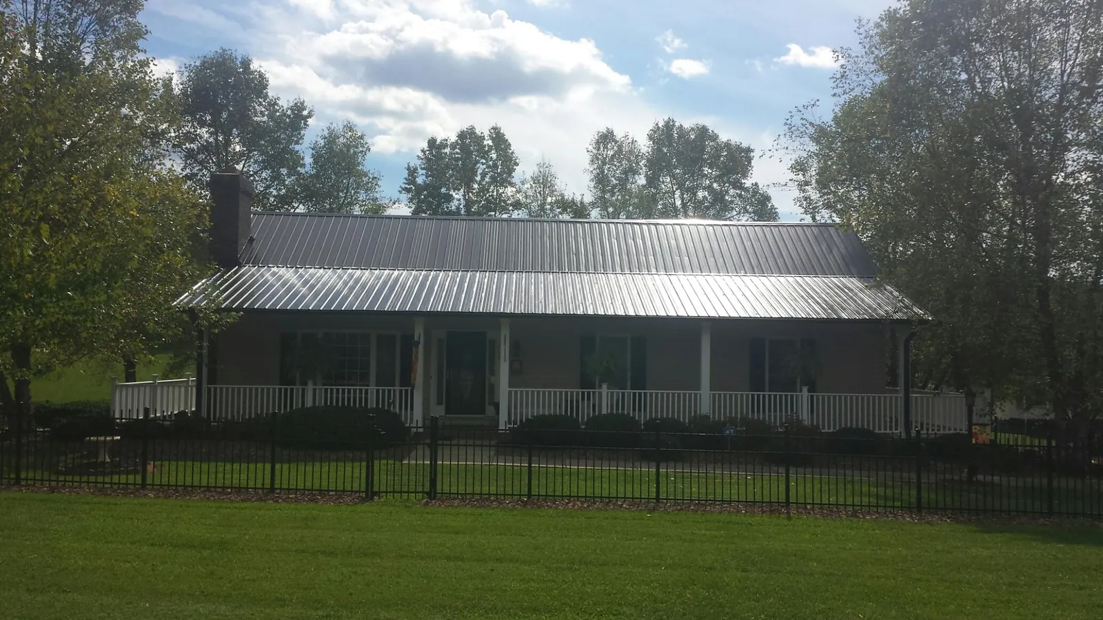 Gray metal roof on a brick ranch with a full width front porch — Gutter Guard Installation work by our crew in Prague