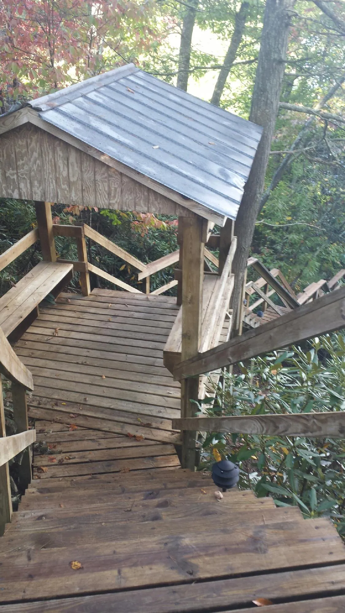 Metal roofed shelter over wooden steps on a wooded walkway — Skylight Repair & Installation work by our crew in Prague