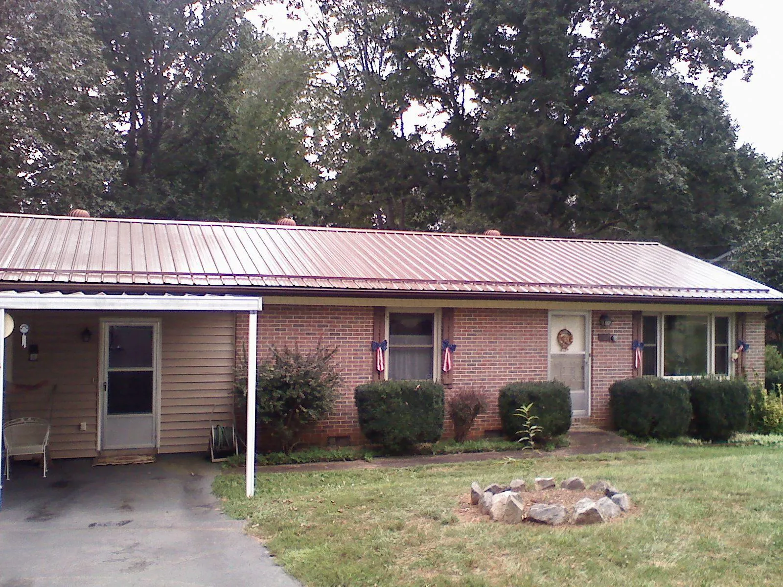 Bronze metal roof and carport on a brick ranch home — Roof Repair work by our crew in Prague